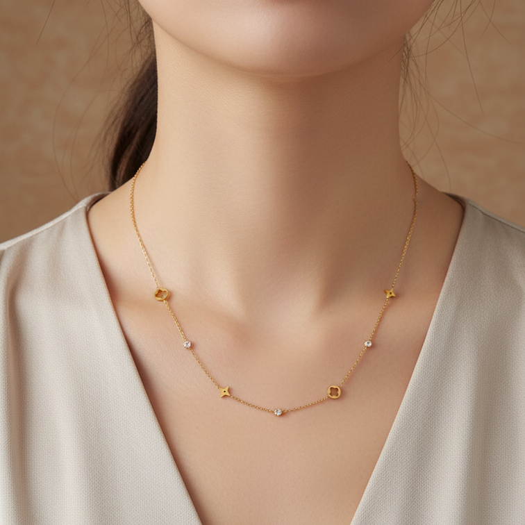 A close-up of a woman wearing a delicate Gold Star & Clover Charm Necklace, paired with a cream-colored V-neck top. The image has a warm, soft-focus aesthetic with a beige background.