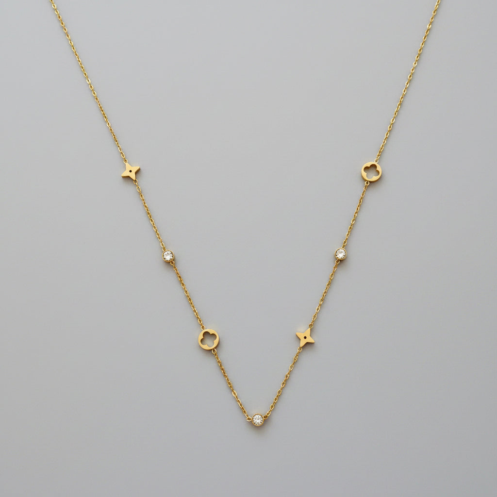 A delicate Gold Star & Clover Charm Necklace, laid flat on a textured white paper towel background.