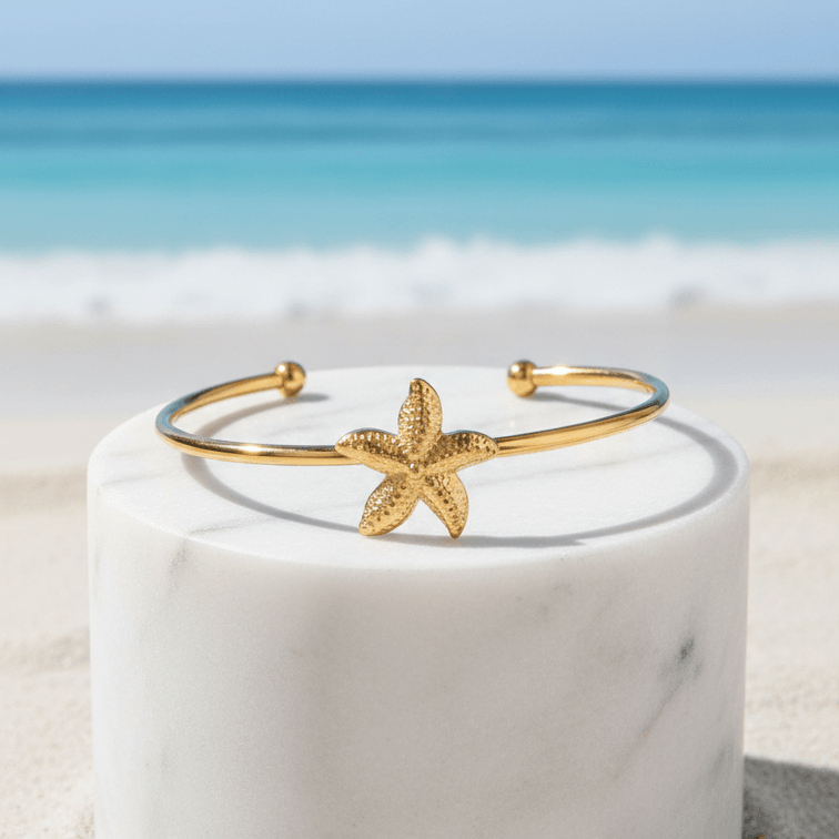 Gold Starfish Bangle Bracelet on pedestal beach background