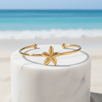 Gold Starfish Bangle Bracelet on pedestal beach background