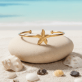 Gold Starfish Bangle Bracelet on stone beach background