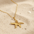 Gold Starfish Pendant Necklace on a sandy surface