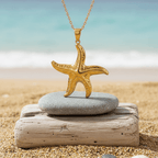 Gold Starfish Pendant Necklace on a stone with a beach background