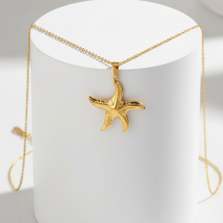 Gold Starfish Pendant Necklace on a white stand with a blurred background