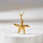 Gold Starfish Pendant Necklace on a white marble base