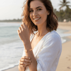 Woman in a white dress standing on a beach with palm trees in the background wearing Gold Starfish & Shell Bangle Bracelet