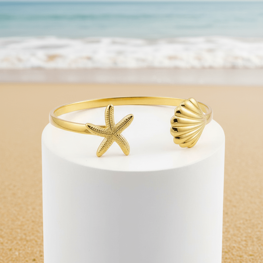 Gold Starfish & Shell Bangle Bracelet with starfish and shell design on a white candle