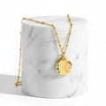 Gold Sunburst Gemstone Necklace with a round sun-face charm featuring blue and clear rhinestones, shown on a white background with text indicating weight, length, and pendant height.
