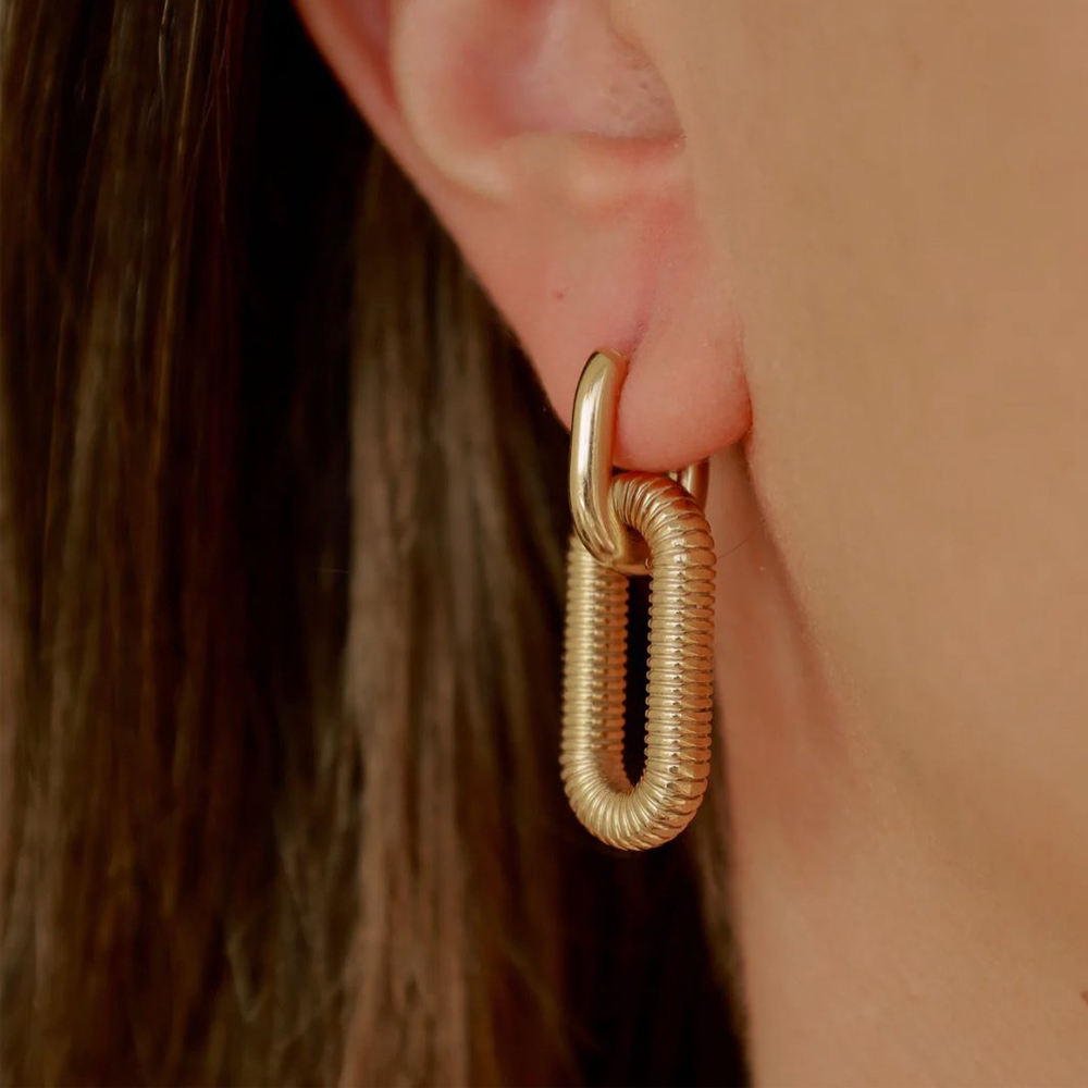 Gold Textured Oval Link Hoop Earrings worn by a person with brown hair.