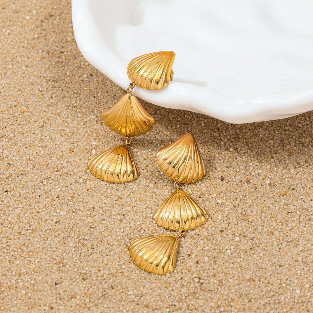 Gold Tiered Seashell Earrings on a sandy background
