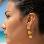 Woman wearing gold earrings with a beach background