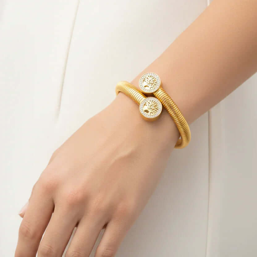 Woman wearing Ceyrah gold Gold Tree of Life Bracelet on wrist against white dress