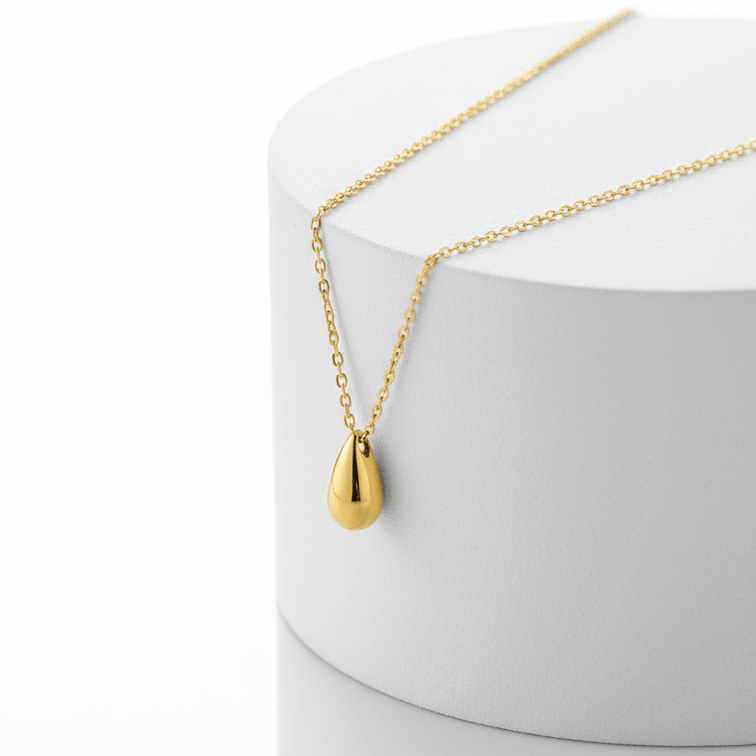 Gold Water Drop Necklace with a teardrop pendant on a white stand