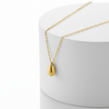 Gold Water Drop Necklace with a teardrop pendant on a white stand