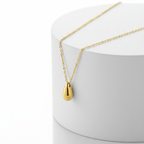 Gold Water Drop Necklace with a teardrop pendant on a white stand