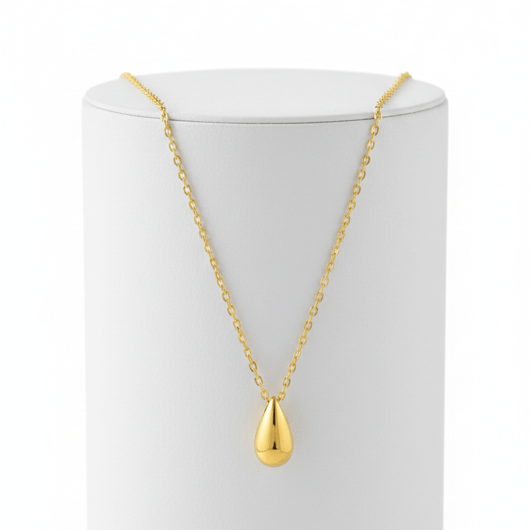 Gold Water Drop Necklace with a teardrop pendant on a white stand