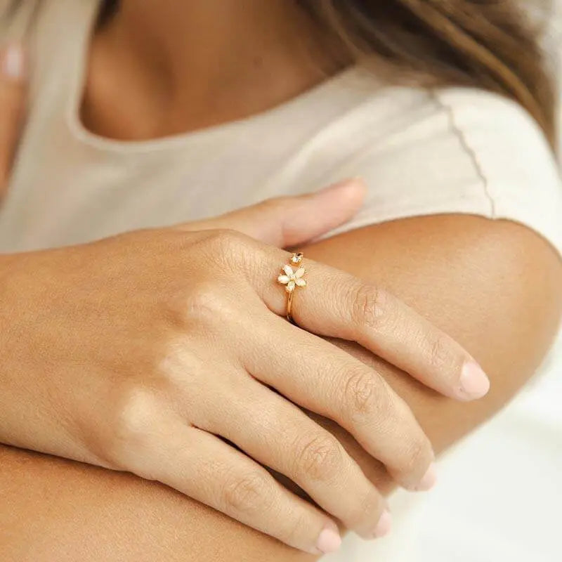 Close-up of a woman's hand wearing a Dainty Bloom Open Gold Adjustable Ring, with a blurred background.