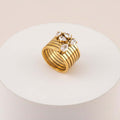 Stacked Gold Teardrop Ring featuring layered bands and clear teardrop-shaped gemstones on a white pedestal.