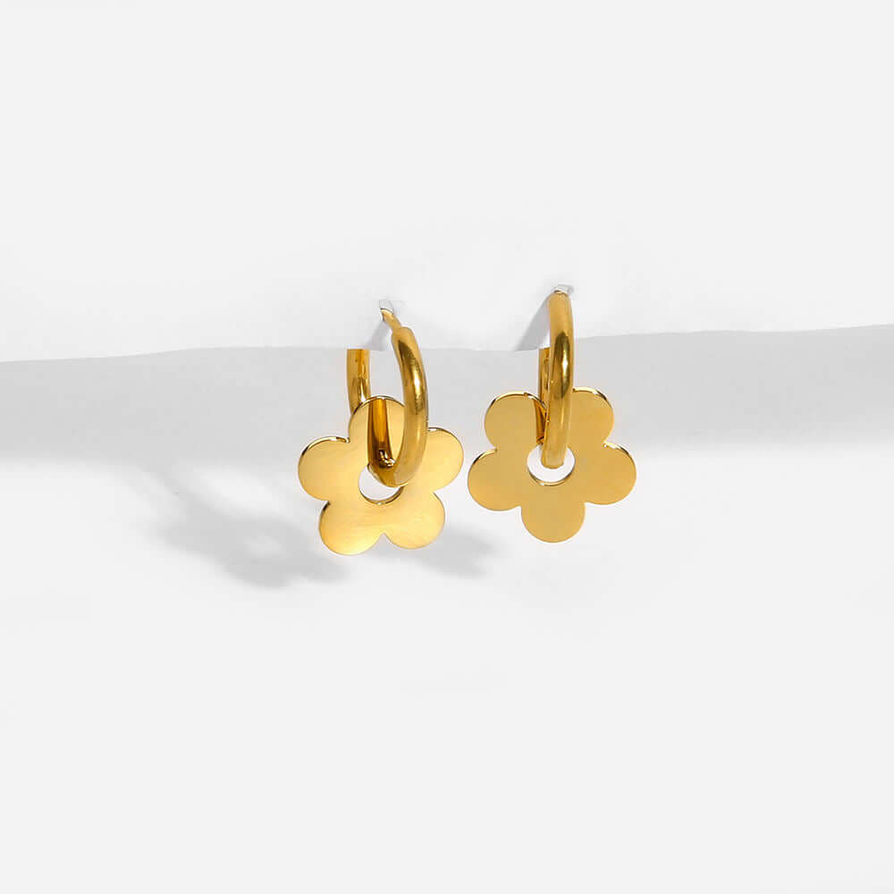 Ceyrah gold hoop earrings with flower-shaped charms on white background