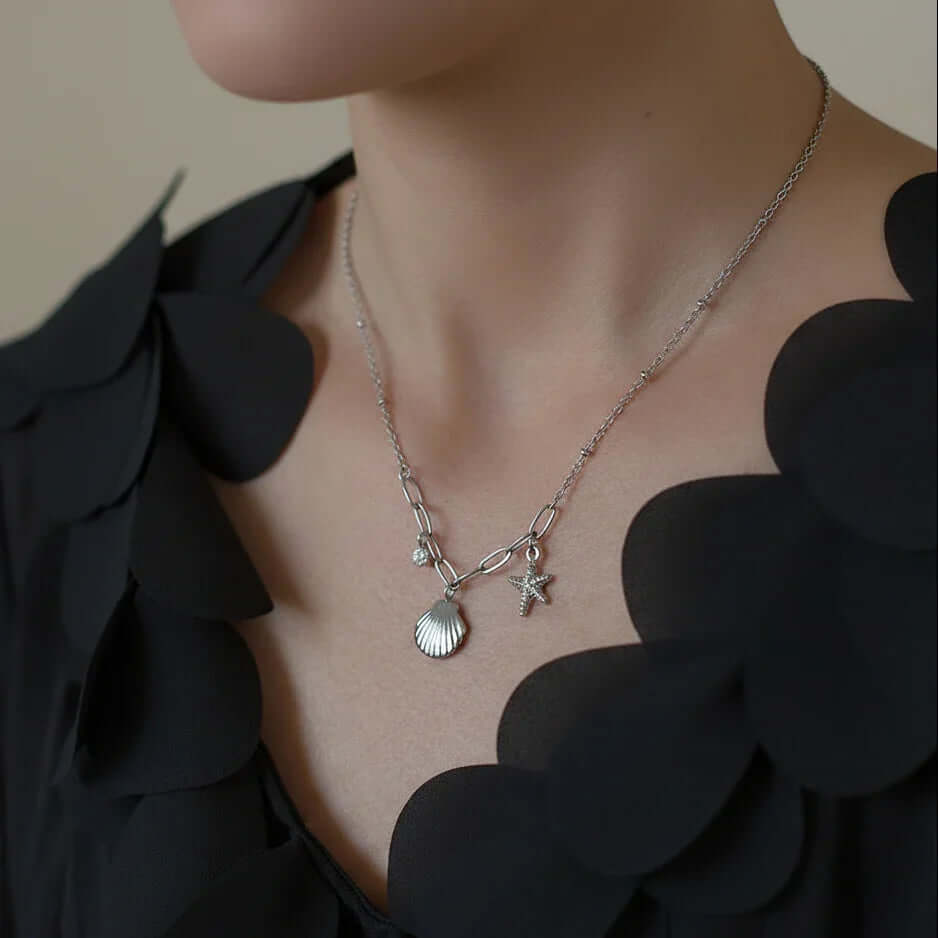 Woman wearing a silver seashell charm necklace with starfish pendant, Ceyrah jewelry