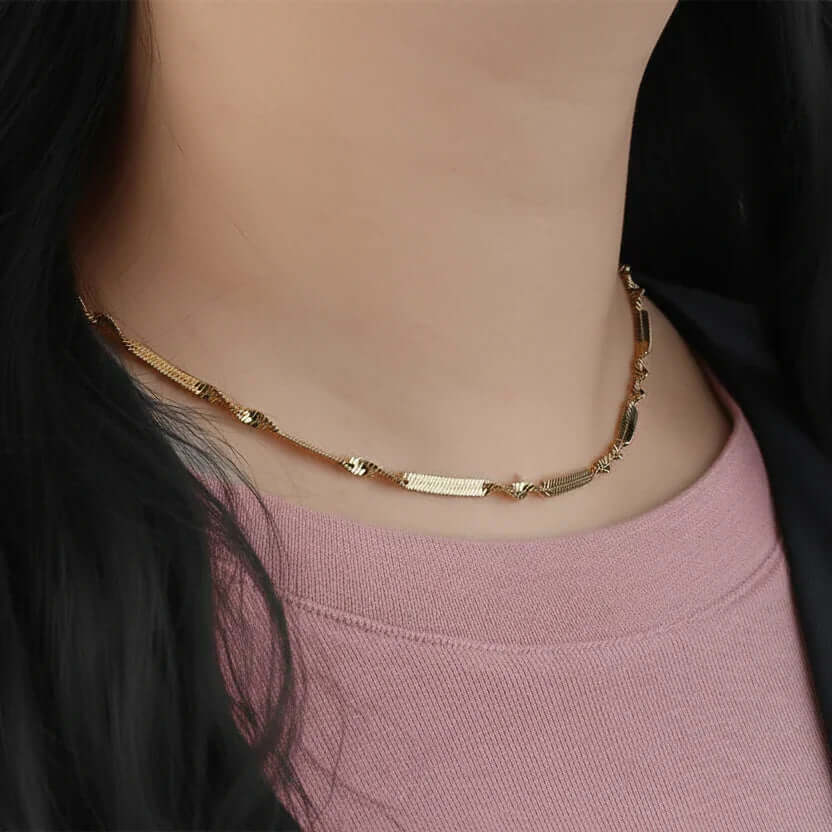 Gold chain necklace on woman, Ceyrah jewelry accessory, close-up against pink top