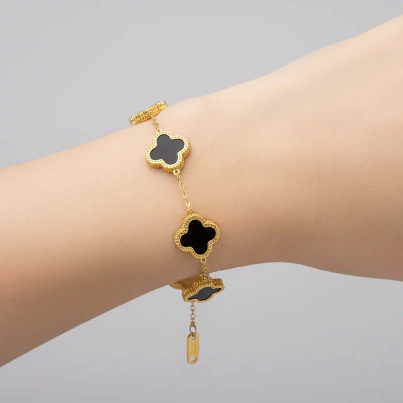 Gold bracelet with black clover charms on wrist, Ceyrah jewelry collection
