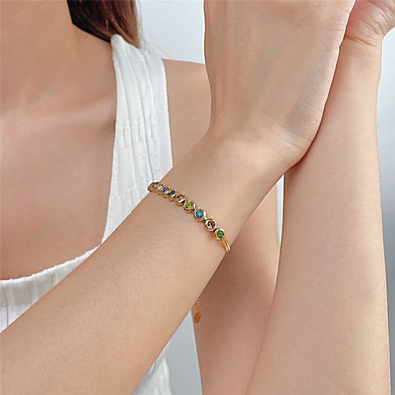 Woman wearing a gold bracelet with colorful gemstones, Ceyrah fashion jewelry