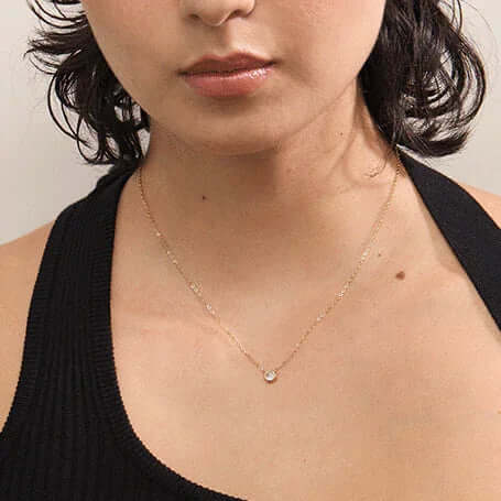 Woman wearing a delicate gold necklace with small pendant, Ceyrah jewelry