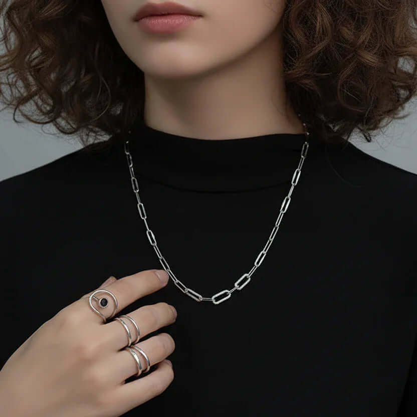 Woman wearing Ceyrah silver chain necklace and rings, black top, close-up jewelry