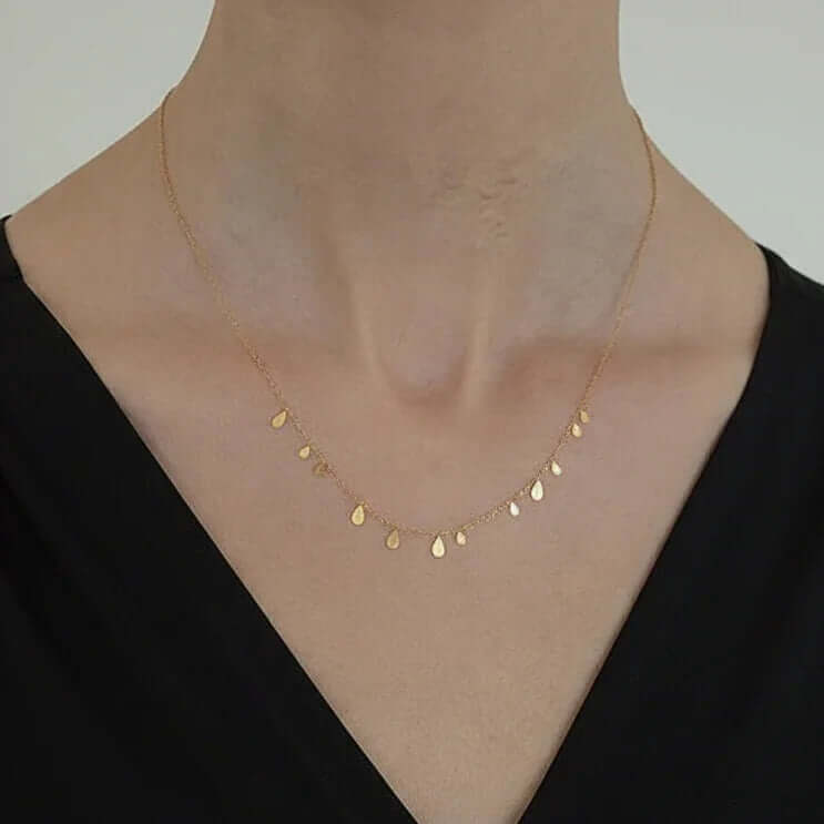 Gold teardrop charm necklace on model wearing black top, Ceyrah minimalist jewelry