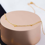Ceyrah gold chain necklace with three small heart charms on pedestal