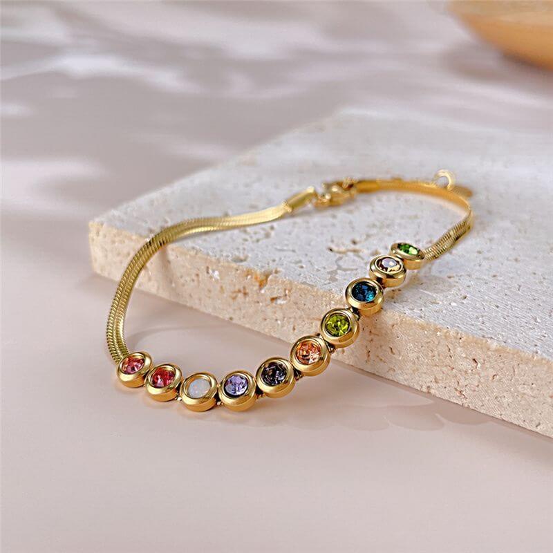 Ceyrah gold bracelet with colourful gemstones, adjustable chain, on surface