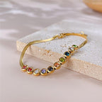 Ceyrah gold bracelet with colourful gemstones, adjustable chain, on surface