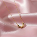 Gold hexagon bead necklace from Ceyrah on pink satin background
