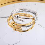 Elegant Bread Nail Bangle Bracelet set in gold and silver on a reflective surface, showcasing modern jewelry design.