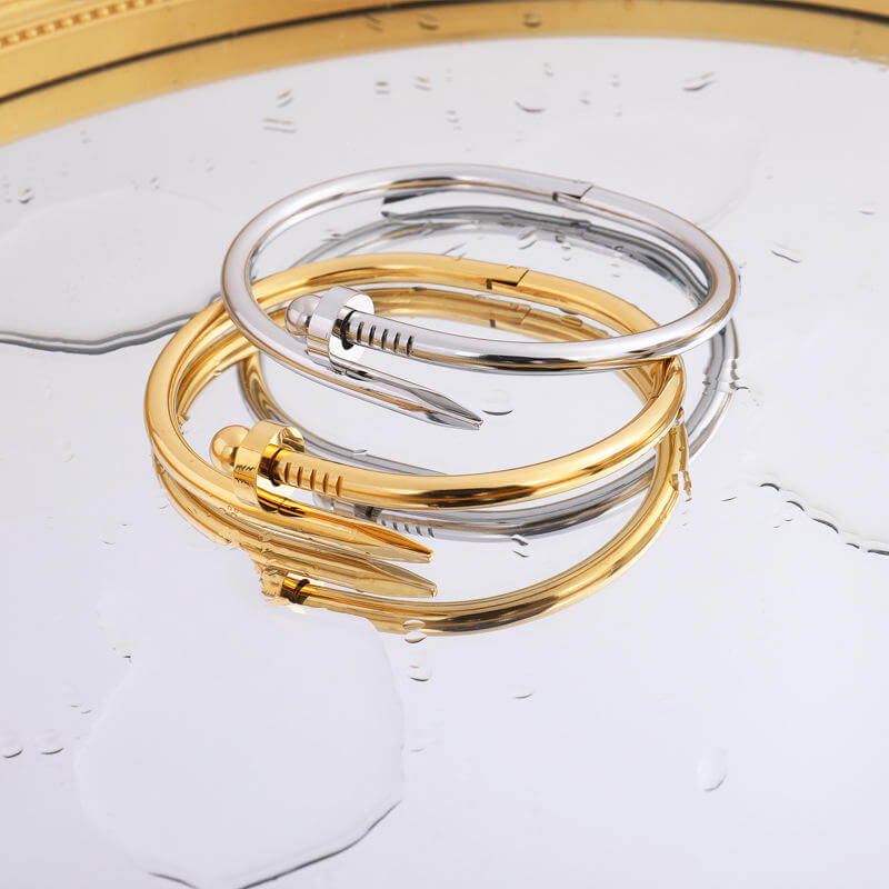 Elegant Bread Nail Bangle Bracelet set in gold and silver on a reflective surface, showcasing modern jewelry design.