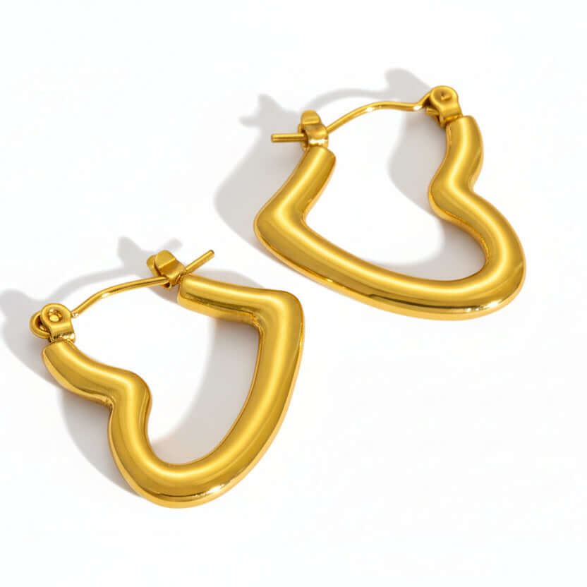 Gold hoop earrings on a beige stone surface