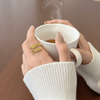 Aurelia Leaf Adjustable Gold Ring on model hand with coffe