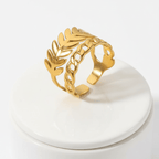 Gold Leaf & Chain Adjustable Ring displayed on a white pedestal showcasing its dual-motif design.