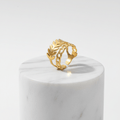 Gold Leaf & Chain Adjustable Ring displayed on a marble pedestal, showcasing its elegant dual-motif design.