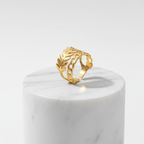 Gold Leaf & Chain Adjustable Ring displayed on a marble pedestal, showcasing its elegant dual-motif design.