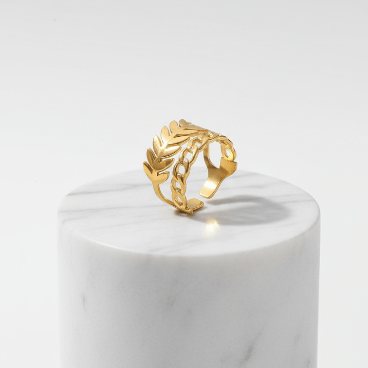 Gold Leaf & Chain Adjustable Ring displayed on a marble pedestal, showcasing its elegant dual-motif design.