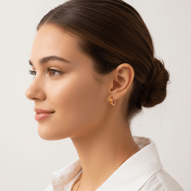 Woman with styled hair and wearing Gold Enamel Huggie Hoop Earrings against a plain background