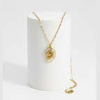 Gold Conch Shell Pendant Necklace displayed on a stand, showcasing its spiral design and elegant gold finish.