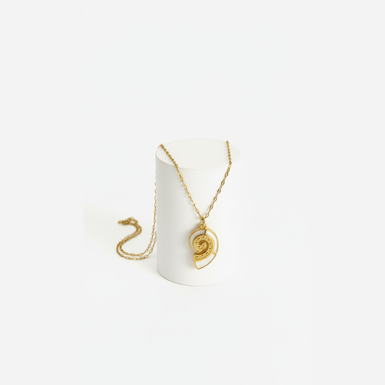 Gold Conch Shell Pendant Necklace displayed on a pedestal, showcasing its coastal elegance and detailed spiral design.