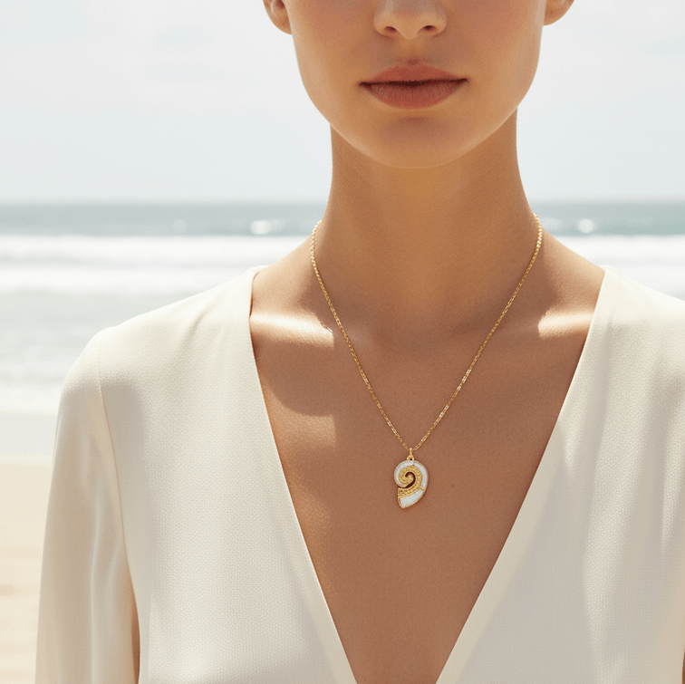 Gold Conch Shell Pendant Necklace worn by a woman on a beach, showcasing the elegant spiral design and shimmering inlay.