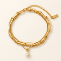 A gold-toned Layered Paperclip Chain Pearl Charm Bracelet, displayed on a clean off-white background.