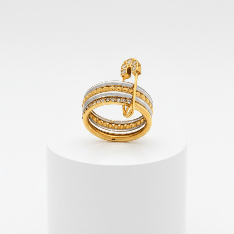 Layered Gold & Silver Safety Pin Ring on a white pedestal with a white background