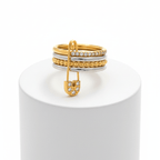 Layered Gold & Silver Safety Pin Ring on a white cylindrical stand with a white background