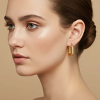 Woman wearing Ceyrah mini gold square hoop earrings with a smooth finish
